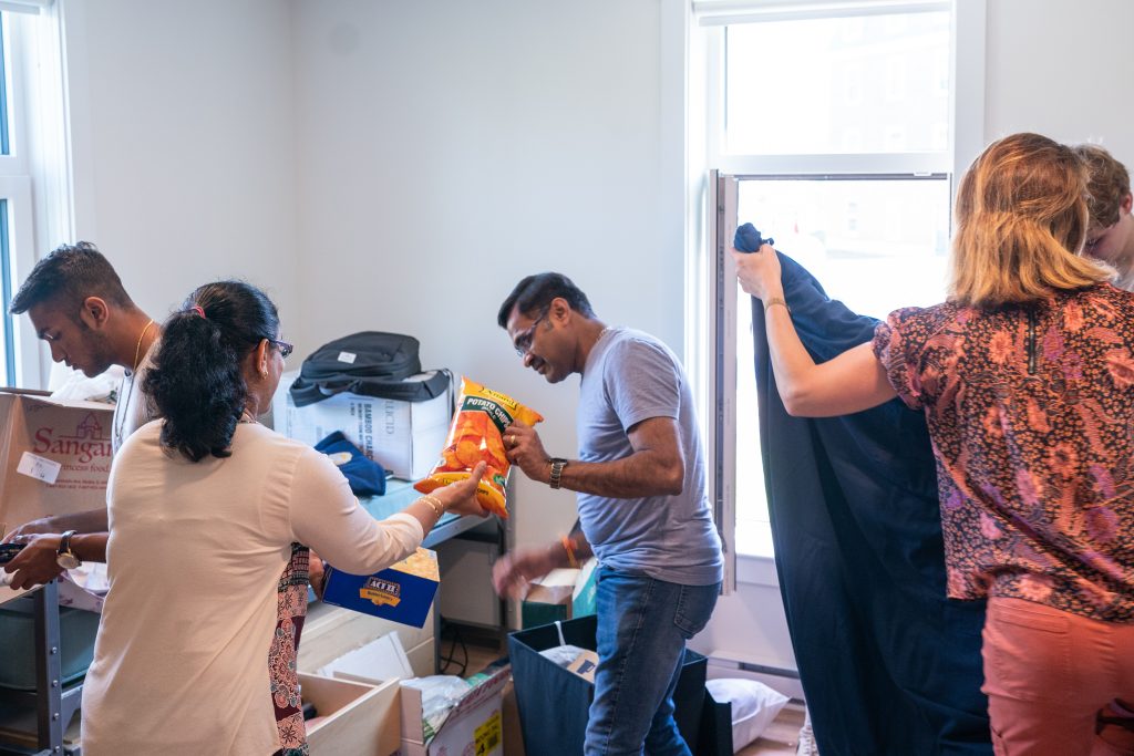 A student and two adults are packing belongings into boxes while moving out of the residence hall.