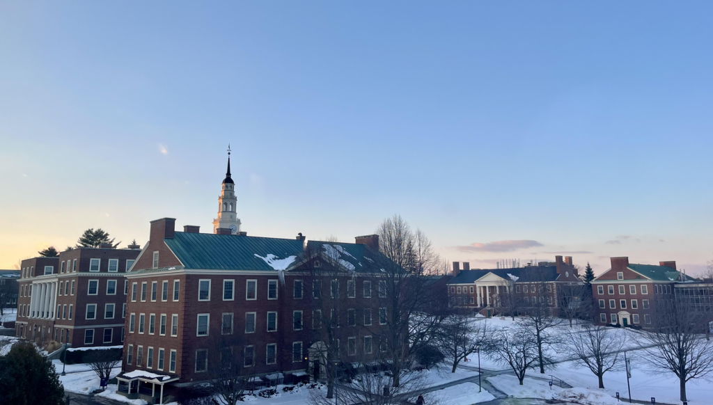 Campus buildings with snow under a clear blue sky at sunset, featuring a prominent steeple and serene winter landscape.